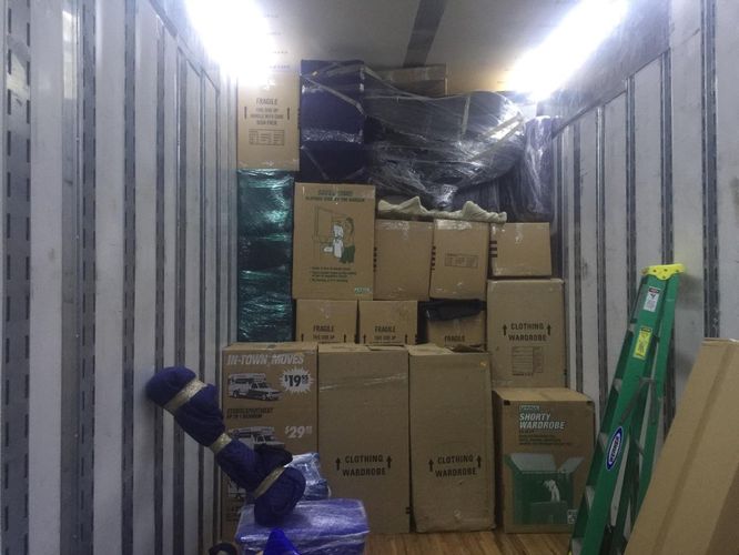 Inside a moving truck: wardrobe boxes, fragile cartons and plastic-wrapped furniture stacked floor to ceiling